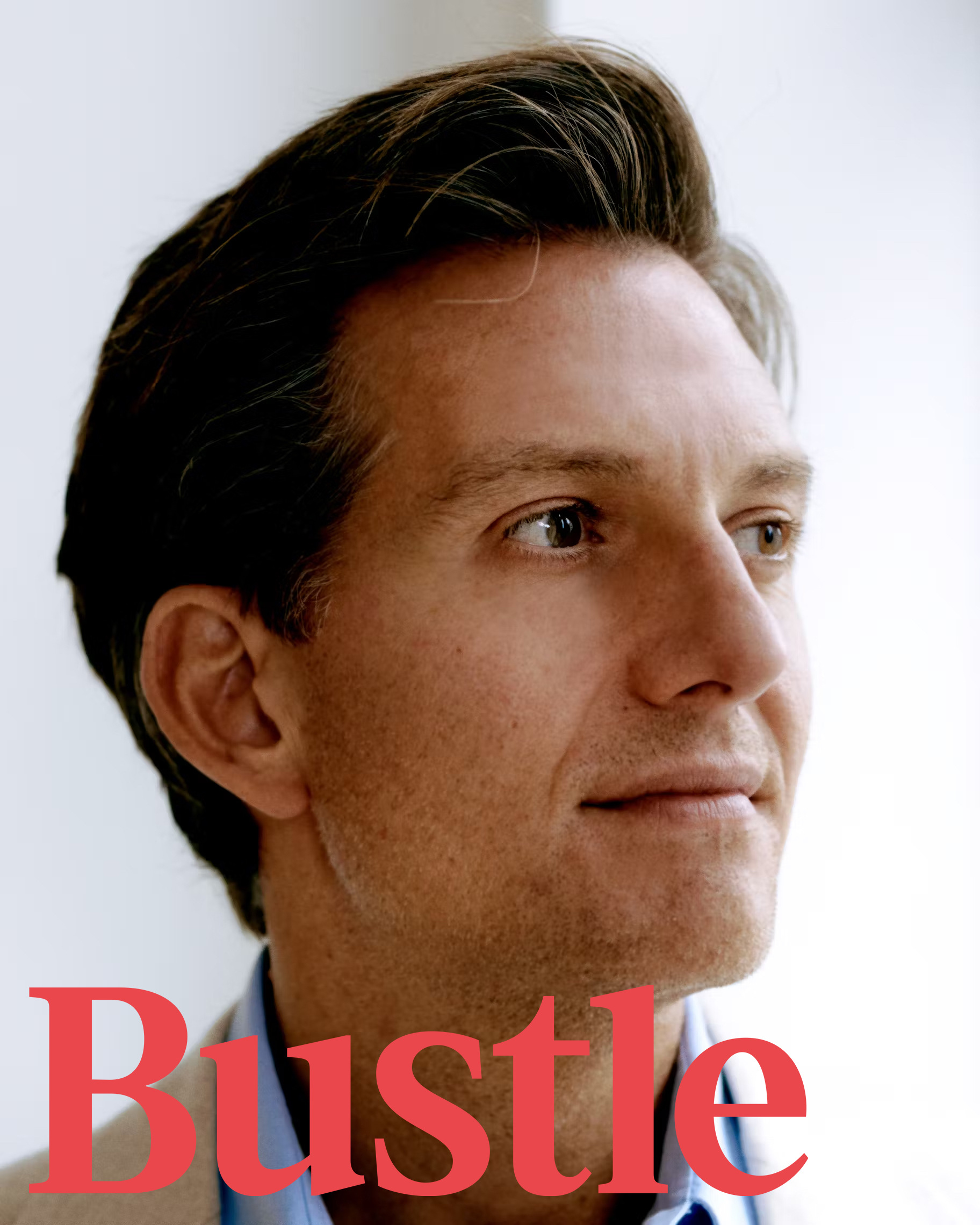 A person with short brown hair looks to the side, captured in a close-up profile against a light background. The word Bustle is in red letters at the bottom of the image.