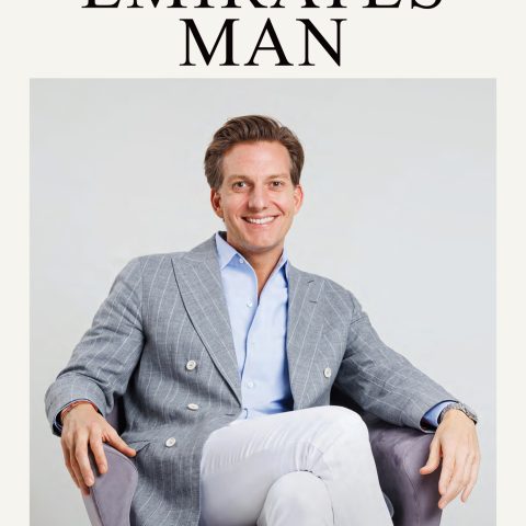 A man in a gray blazer and white pants sits confidently in a gray chair, smiling. The cover text reads Emirates Man with a feature on Dr. Michael Apa, Founder of Apa Aesthetic. The theme is The Winter Escape Issue.