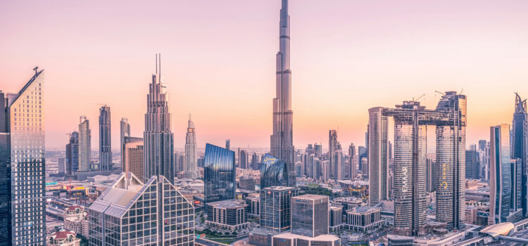 A cityscape of Dubai at sunset, featuring modern skyscrapers, including the iconic Burj Khalifa, under a pinkish sky. Urban architecture and highways weave through the city in the foreground.