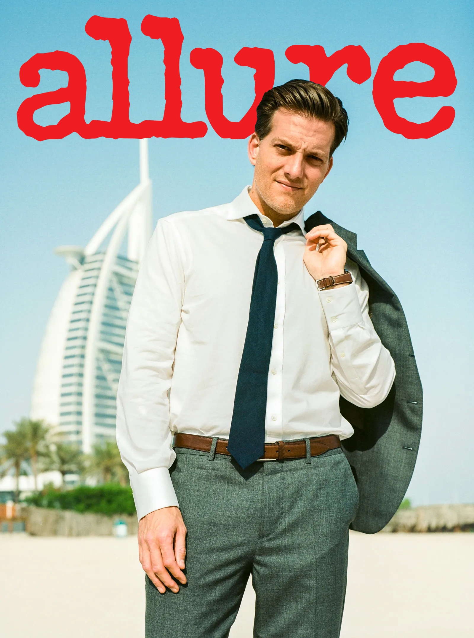 A man in a white shirt and grey suit, holding his jacket over his shoulder, stands on a beach with a modern building in the background. The word allure is in large red letters above him.