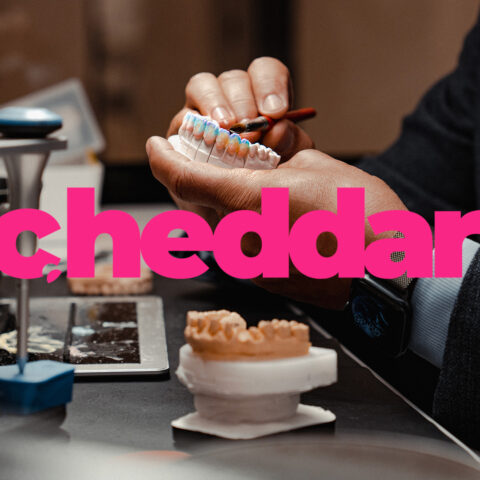 Person working on dental molds at a table with various tools and materials, the word cheddar in bold pink text overlays the image.